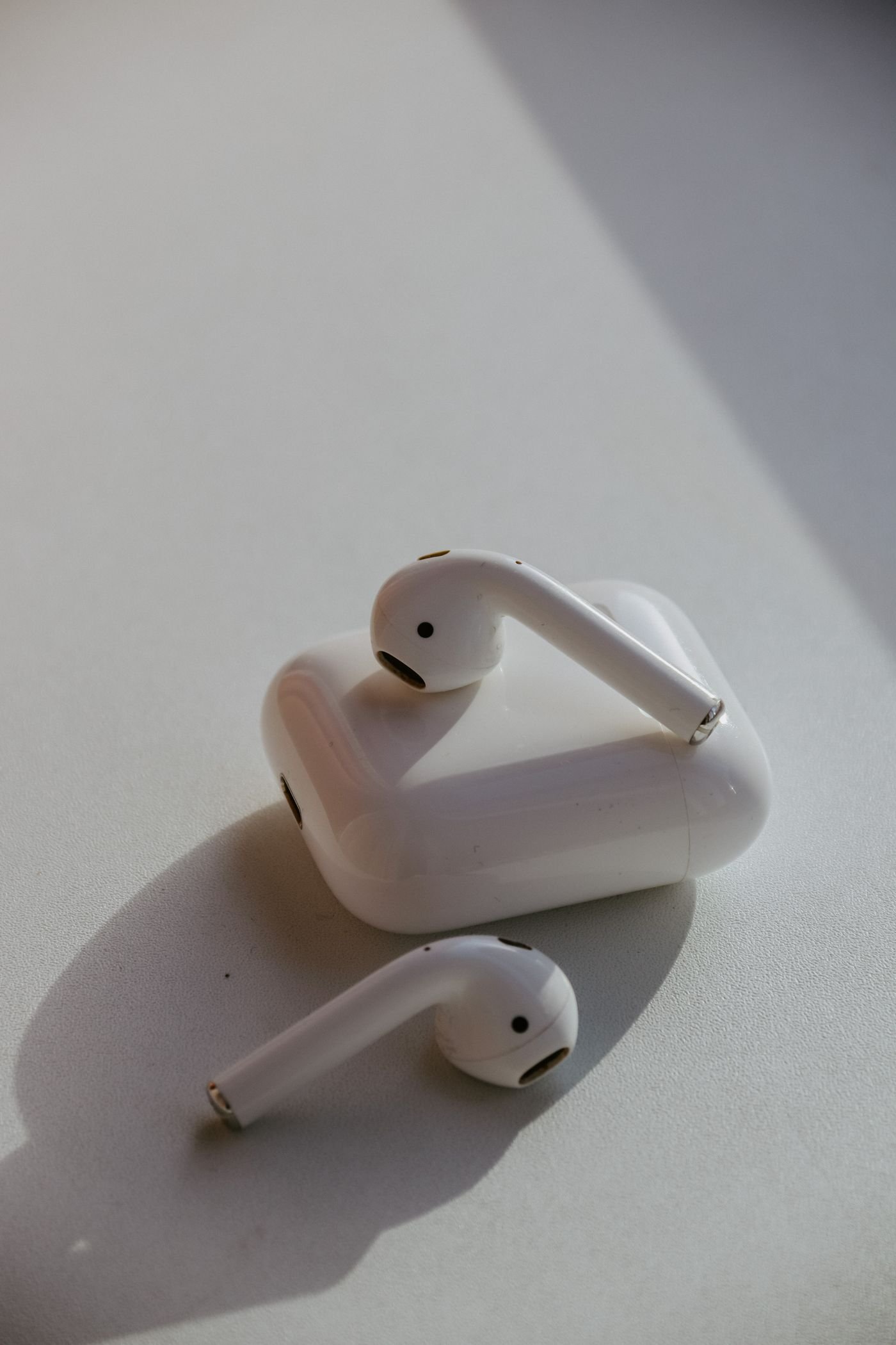 White wireless earbuds resting on and beside a charging case