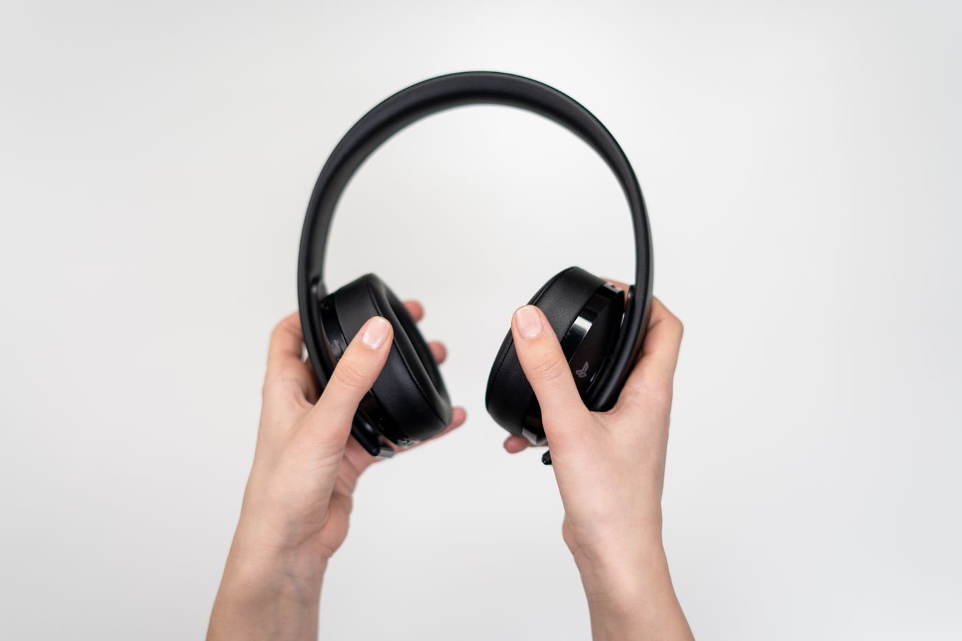 Hands holding black over-ear headphones